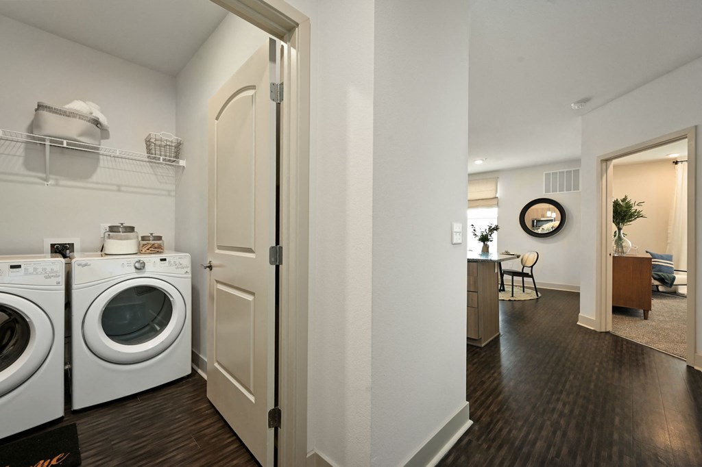 a washer and dryer in a living room with a laundry room door open
