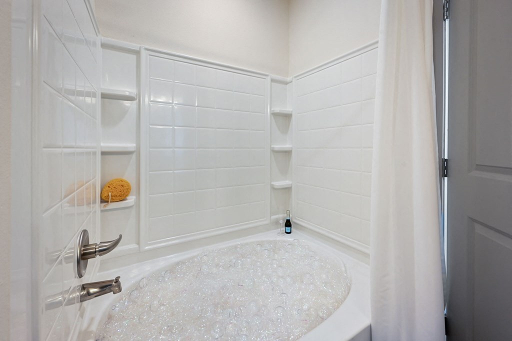 a white shower stall with white tile walls and a shower curtain