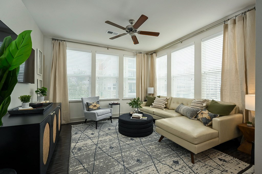 a living room with white blinds and a ceiling fan