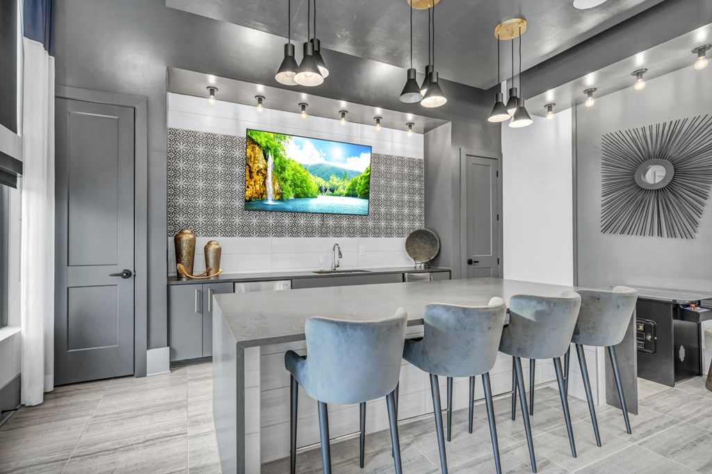 a kitchen with bar stools and a tv on the wall