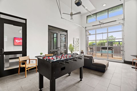 A black pool table in a room with a chair and a TV.