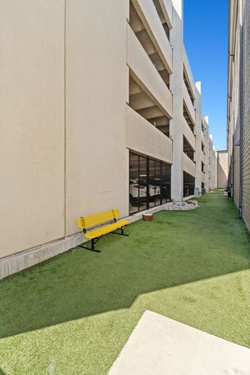 A yellow bench sits on a green lawn in front of a building.