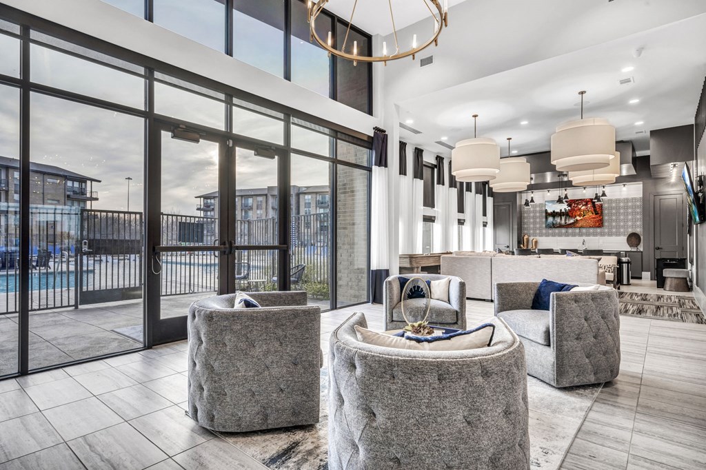 a living room with couches and chairs and large windows