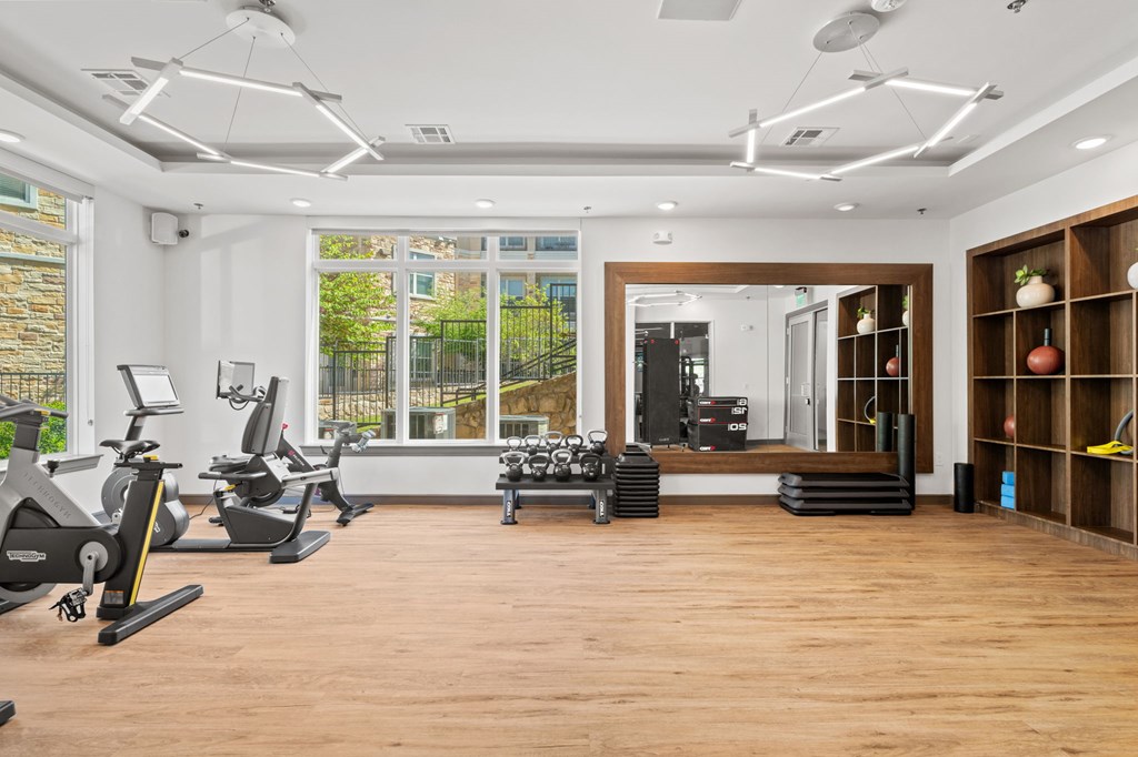 A spacious gym with a variety of exercise equipment and a large mirror on the wall.