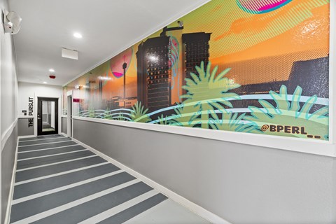 A hallway with a mural on the wall and striped carpeting.