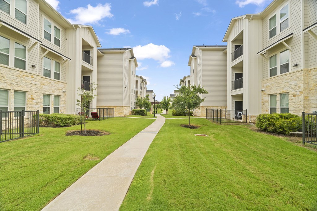 A long concrete walkway leads between two rows of apartment buildings.