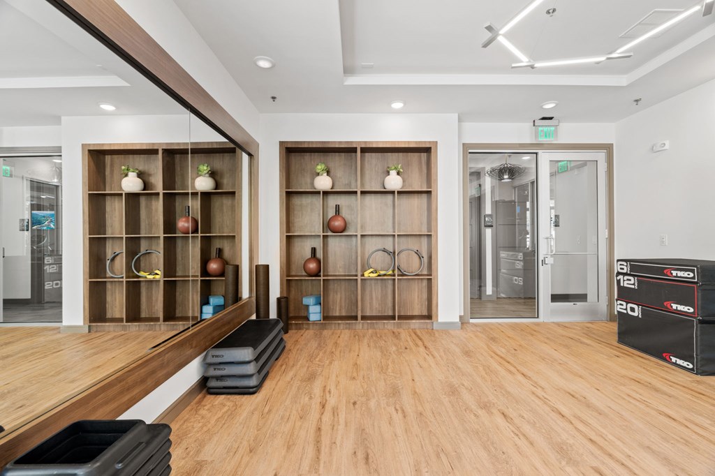 A gym with wooden floors and a variety of exercise equipment.