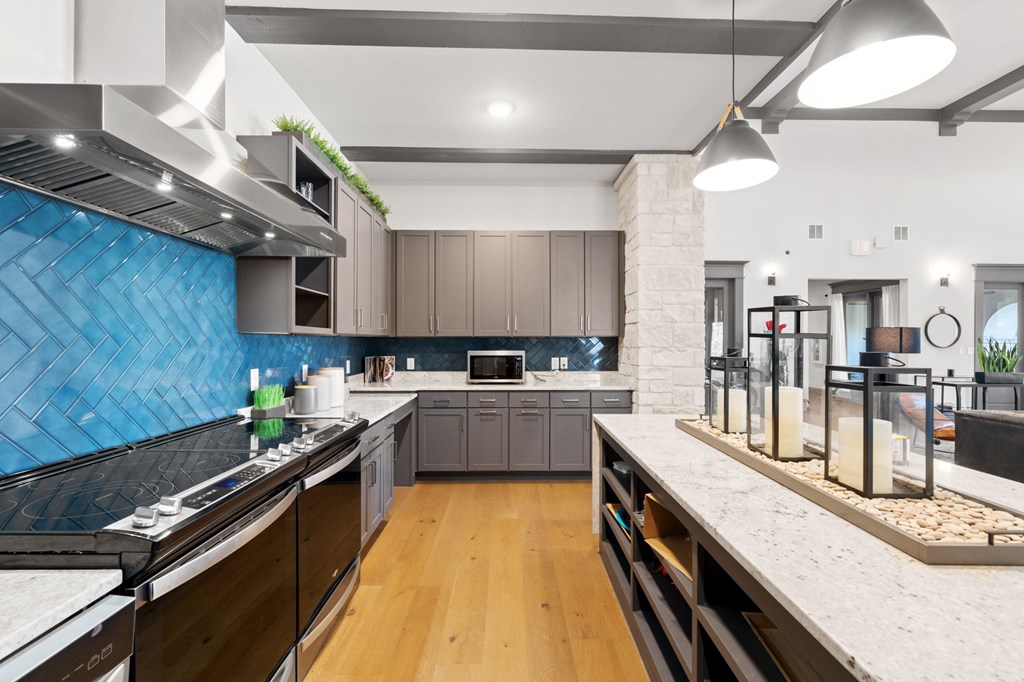 a large kitchen with marble counter tops and blue tile