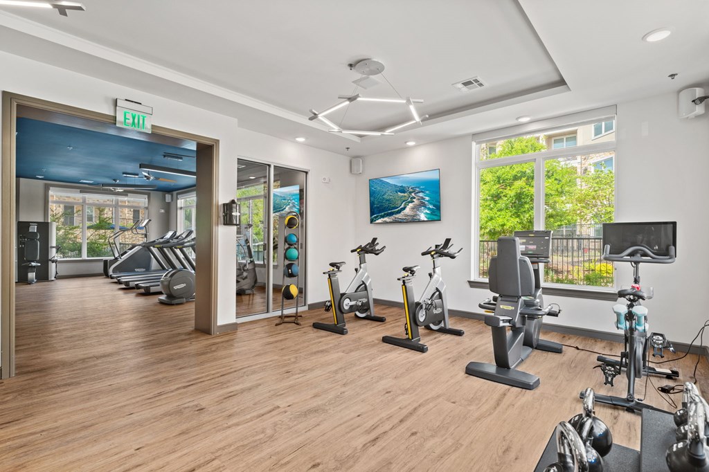 A gym with a variety of exercise equipment and a view of the outside.