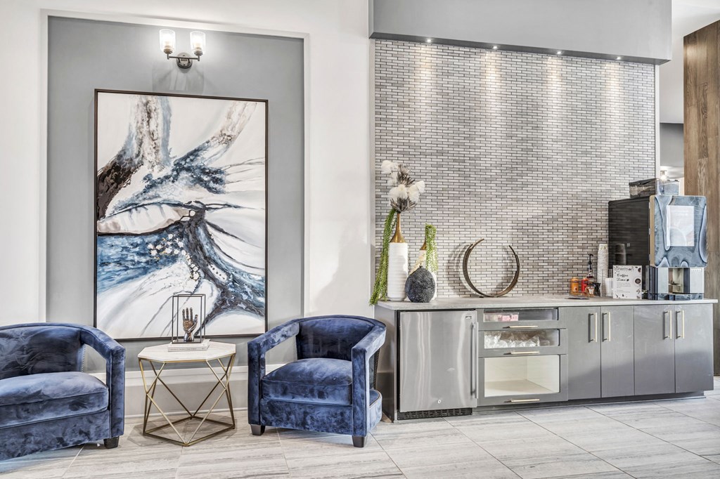 a living room with blue chairs and a bar and a painting on the wall