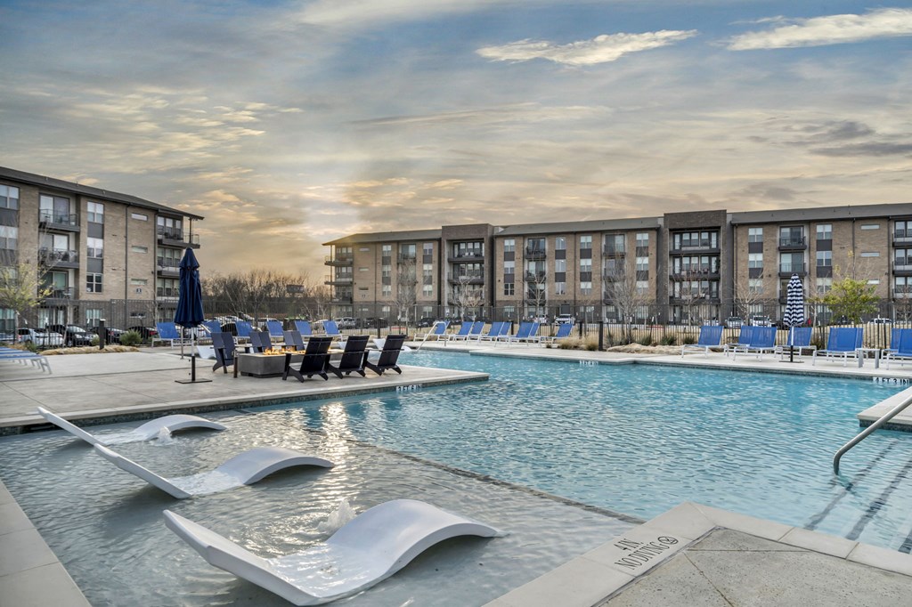 a swimming pool with chairs and umbrellas in front of a building