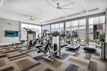 a spacious fitness center with cardio equipment and floor to ceiling windows