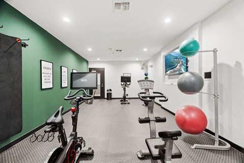 A gym with exercise equipment and a green wall.