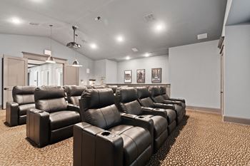 the theater room has a large set of leather couches and chairs