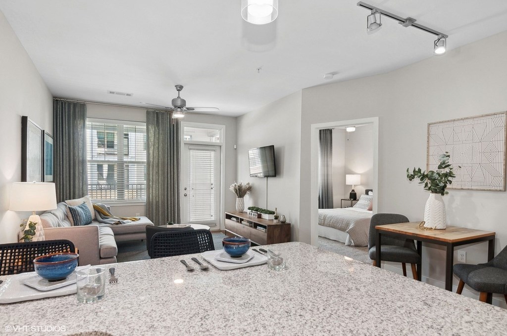 a living room with a kitchen and a bedroom with a couch and a table