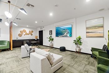 A modern office space with a green chair, a white sofa, and a painting of a beach scene on the wall.