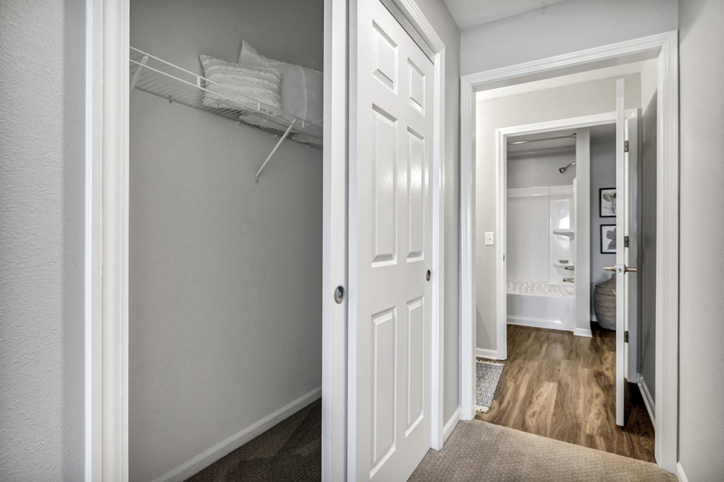 a closet with a white door and a hallway to a bedroom