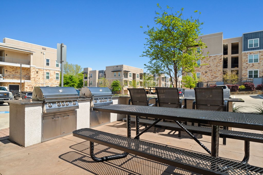 A picnic table and chairs are set up in a courtyard with apartment buildings in the background.