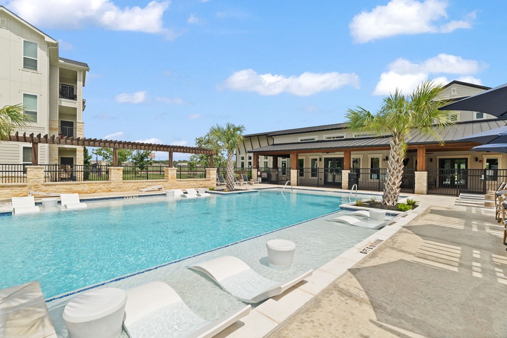A large outdoor swimming pool with lounge chairs and a building in the background.