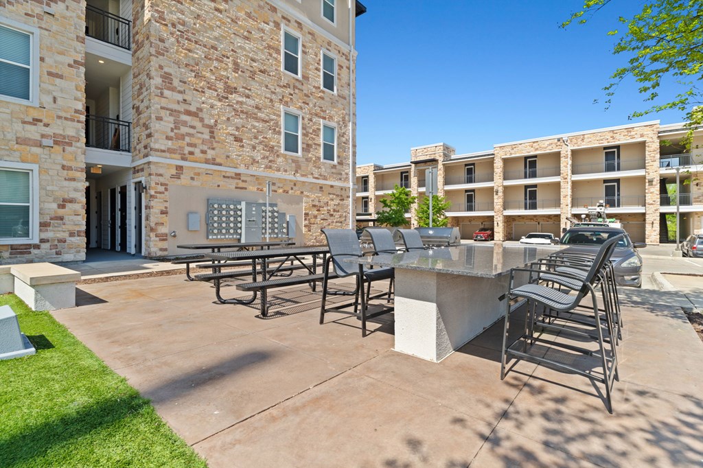 A patio with chairs and a table in front of a building.
