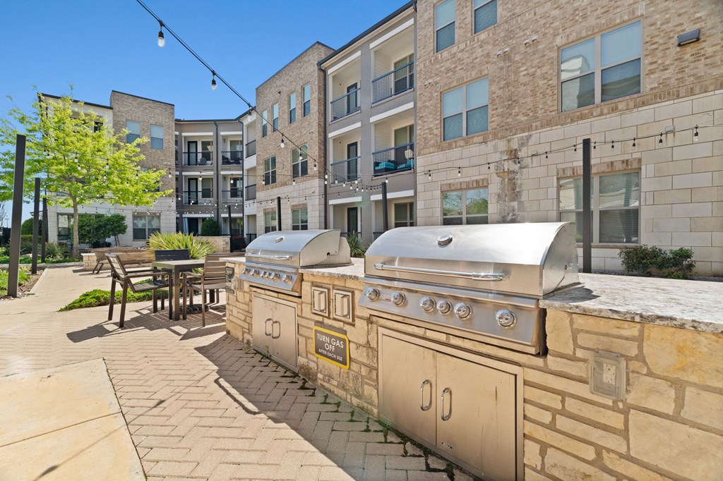 A row of outdoor BBQs are lined up on a patio.