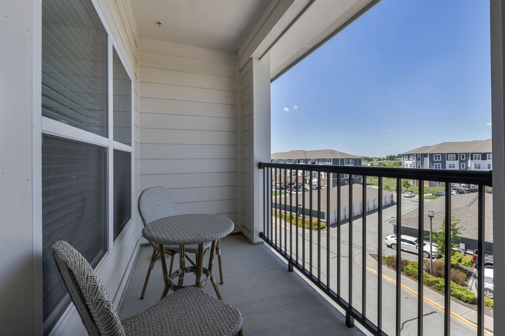 a balcony with two chairs and a table and a large window