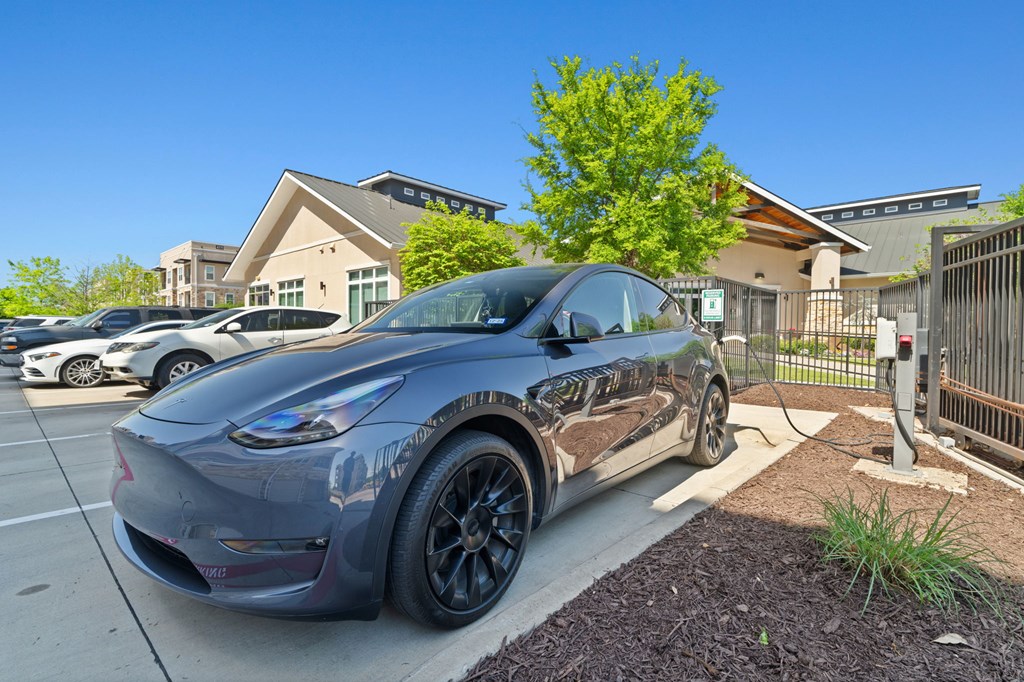 A grey Tesla Model 3 is parked in a parking lot.