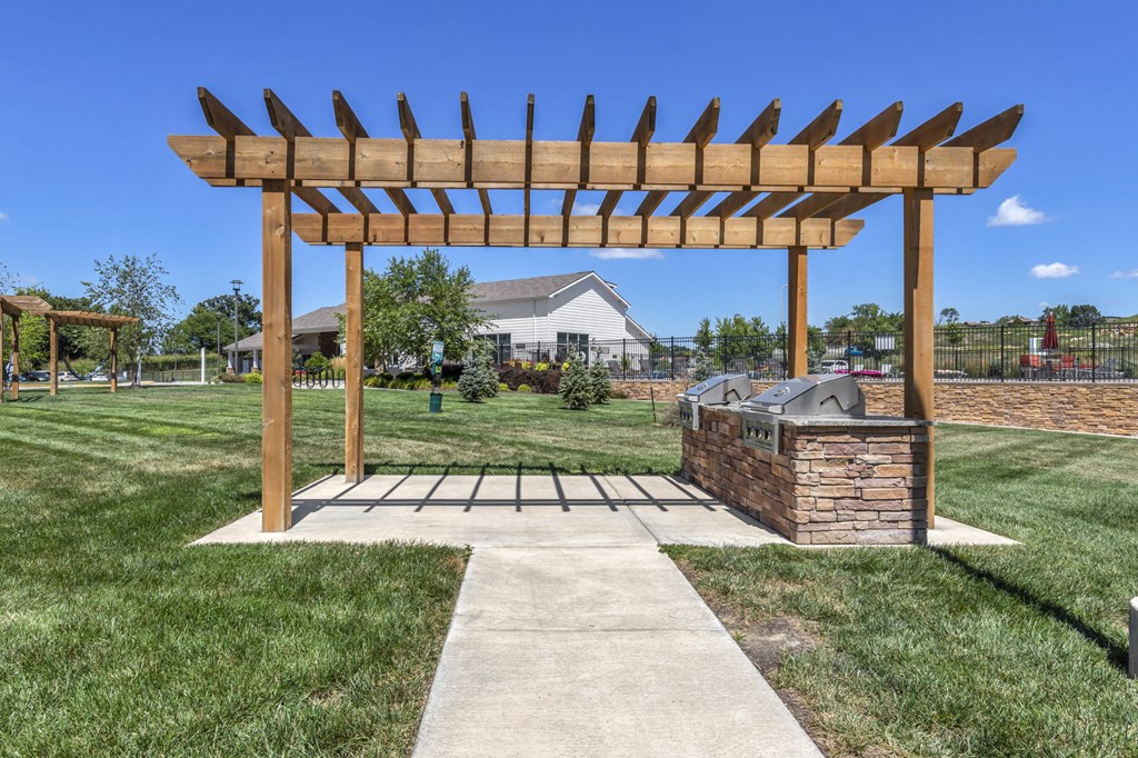 a wooden pergola over a stone barbecue grill in a yard