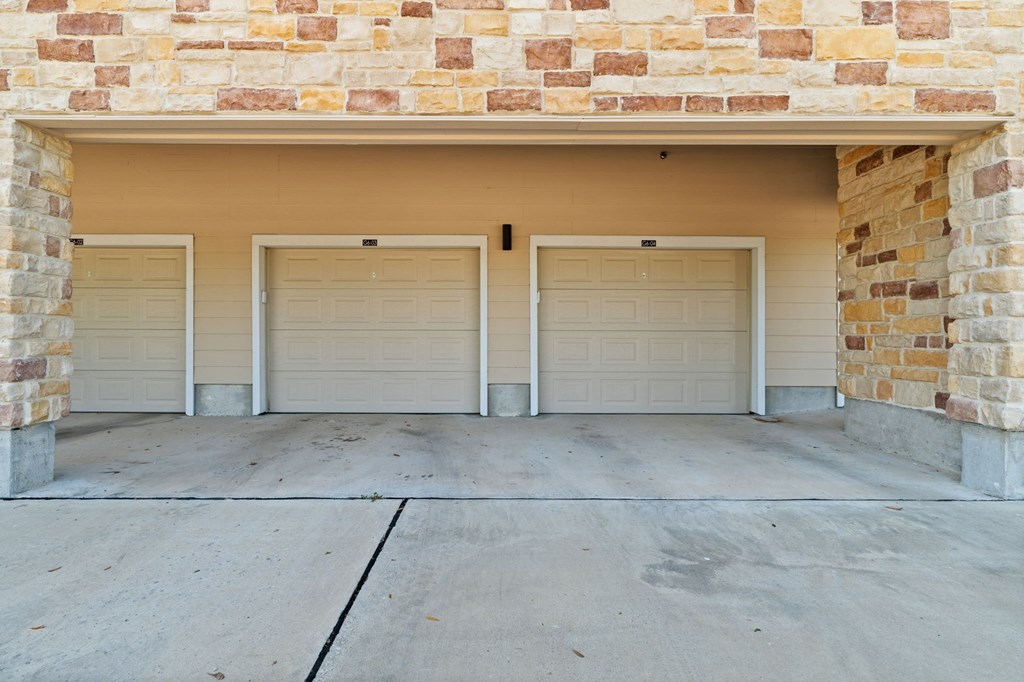 A garage with four doors is framed by a brick wall.