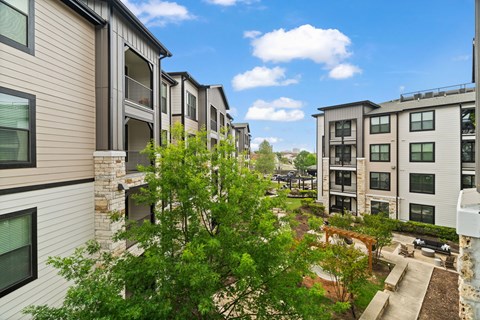 A row of modern apartment buildings with balconies and trees in the foreground.