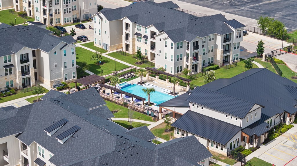 A bird's eye view of a residential area with houses and a swimming pool.