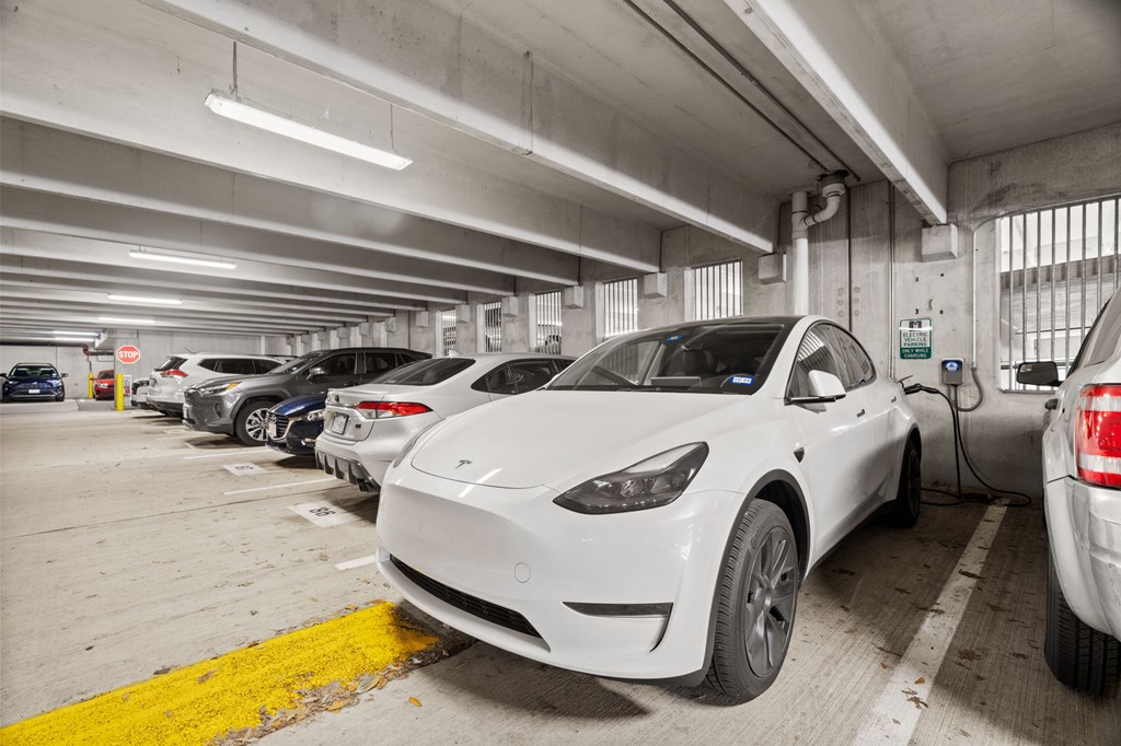 A white Tesla car is parked in a parking garage.
