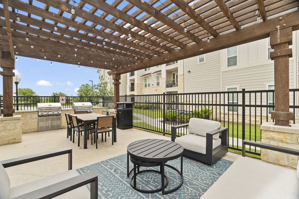 A patio with a table and chairs under a wooden pergola.