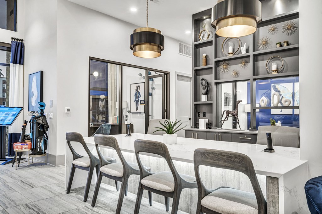 a kitchen with a long white counter and chairs