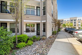 A row of townhouses with a sidewalk and landscaping in front.