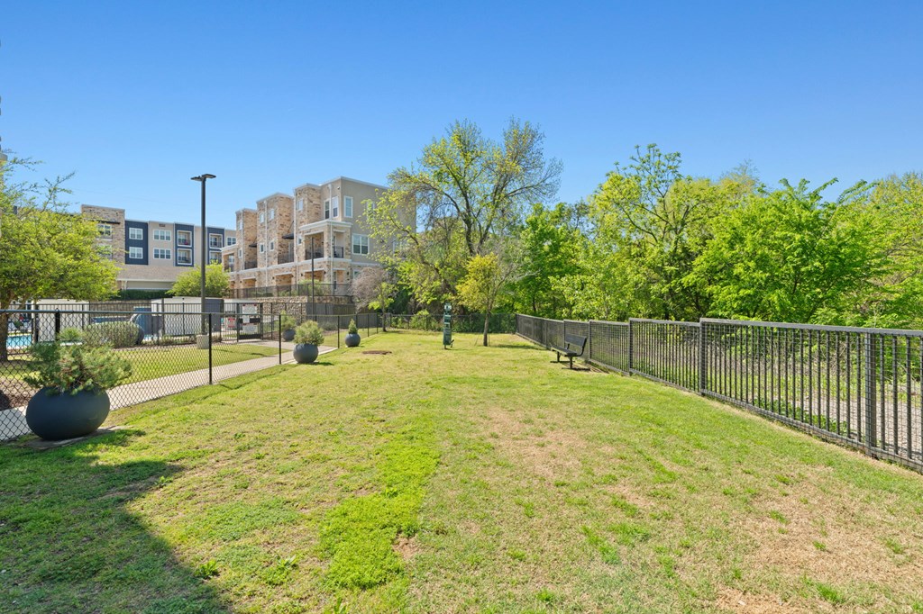 A park with a fence and a bench in front of a building.