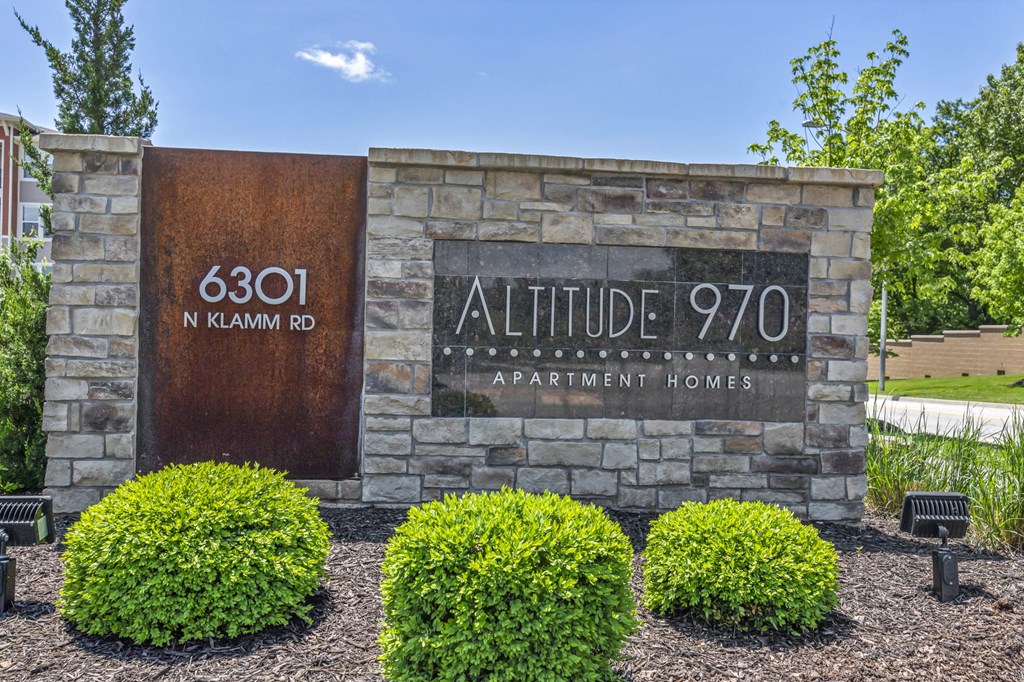 a sign for allittle q70 apartment homes in front of a stone building