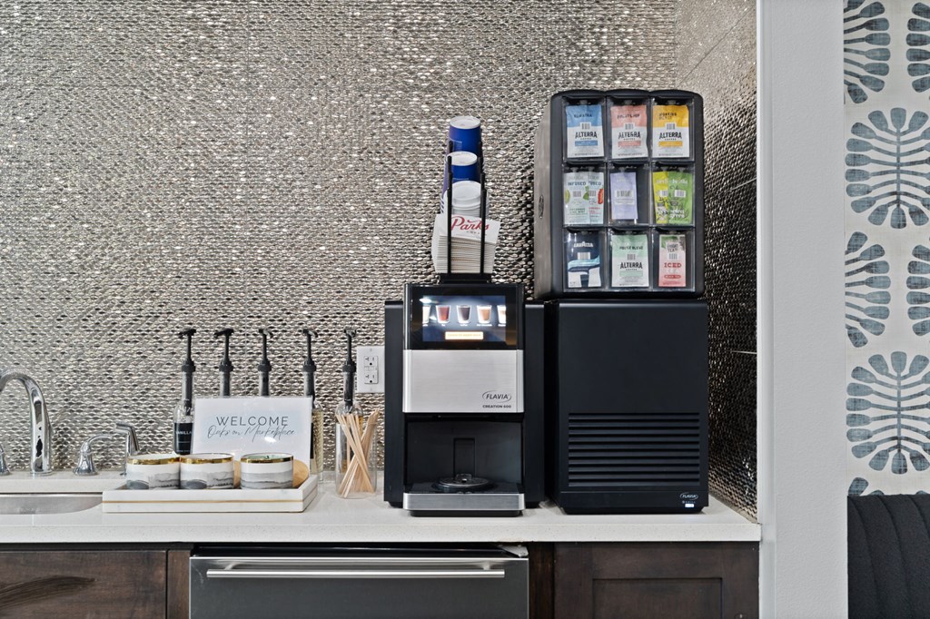 A kitchen counter with a sink, a sign that says "welcome", and a black cabinet with a microwave and a dishwasher.
