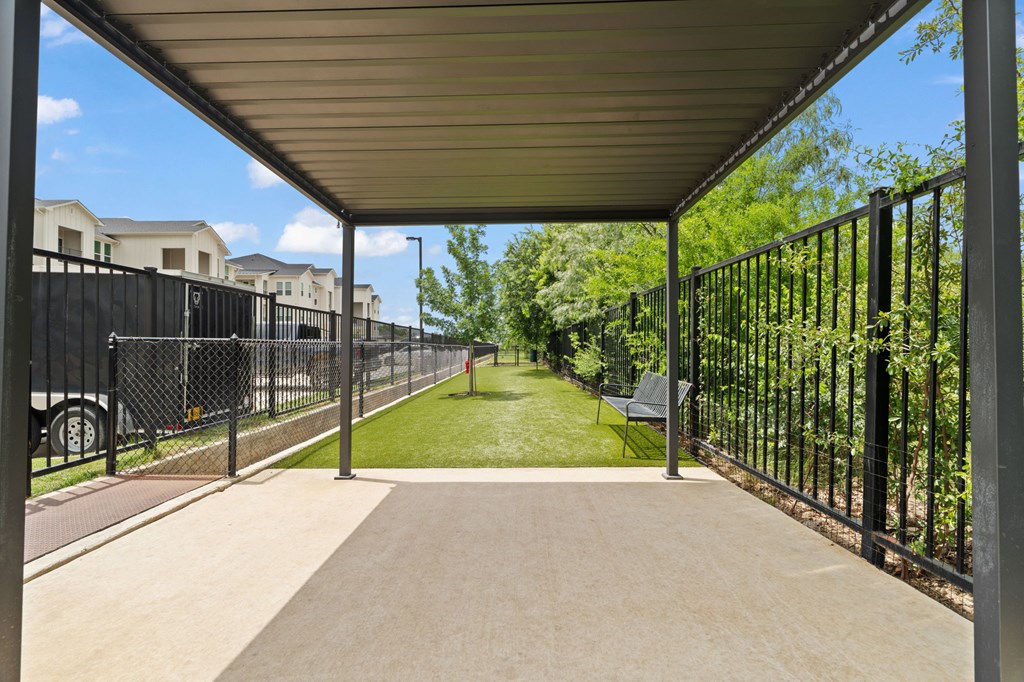 A long concrete walkway with a metal fence on one side and a metal railing on the other.