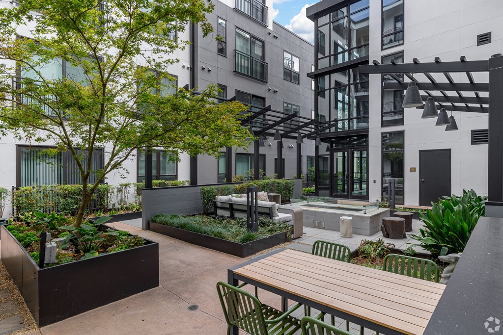 a courtyard with tables and chairs and trees in front of buildings