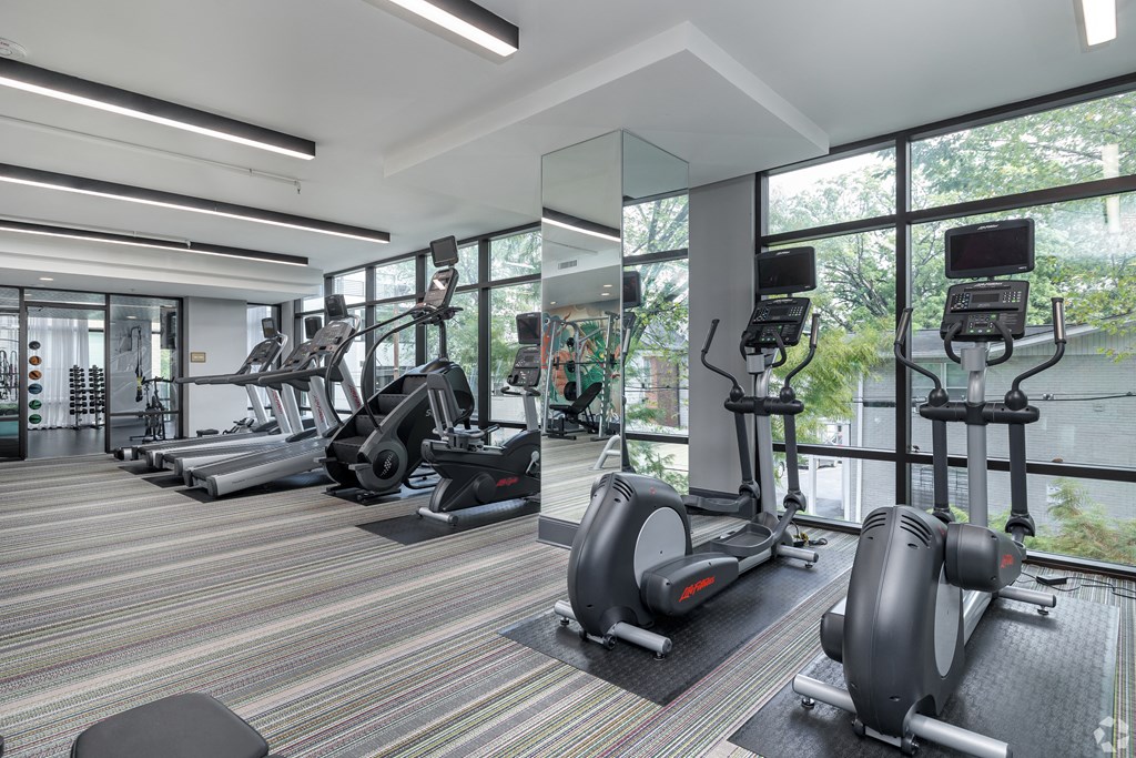 a gym with cardio equipment and floor to ceiling windows