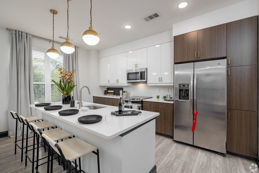 a kitchen with a large island and stainless steel refrigerator