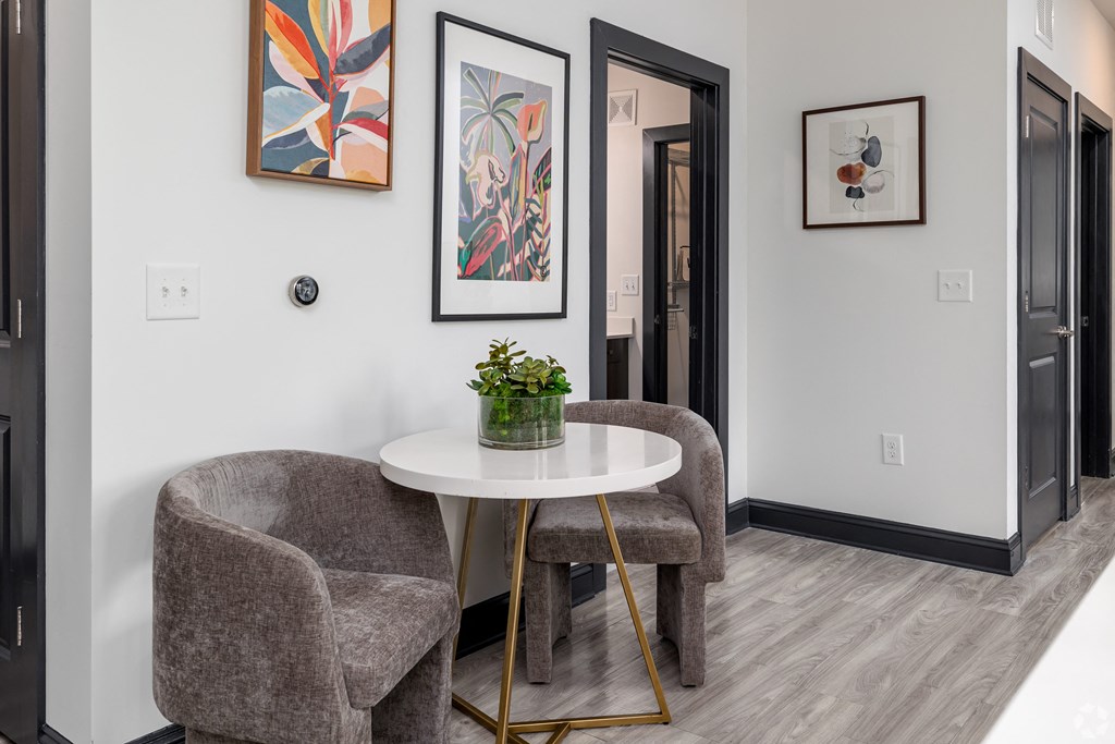 a living room with two chairs and a table and paintings on the wall