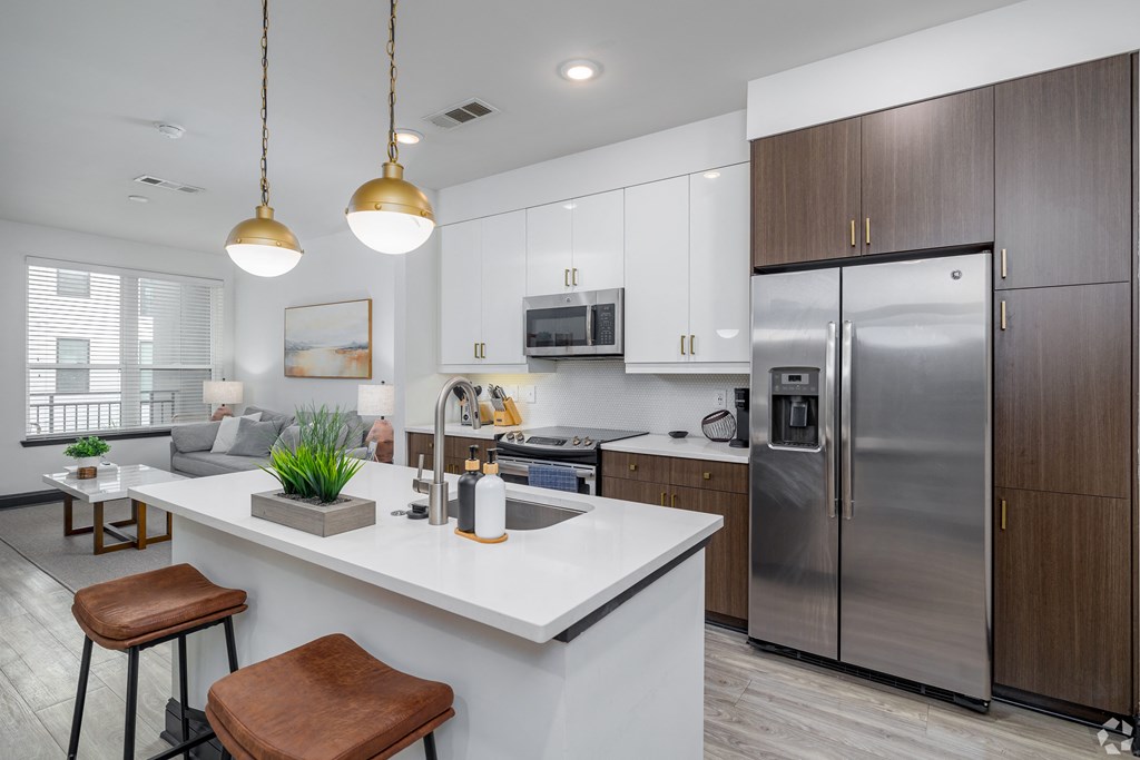 a kitchen with a large island and stainless steel refrigerator