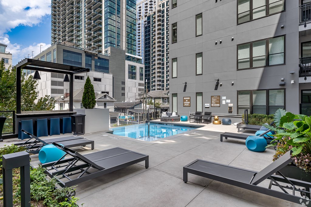 amenities include a pool and lounge chairs at aria on the avenue apartments