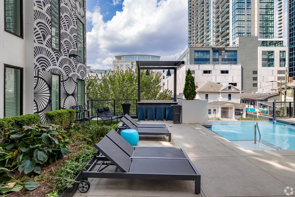 the pool and lounge area of an apartment building with a pool and skyscrapers