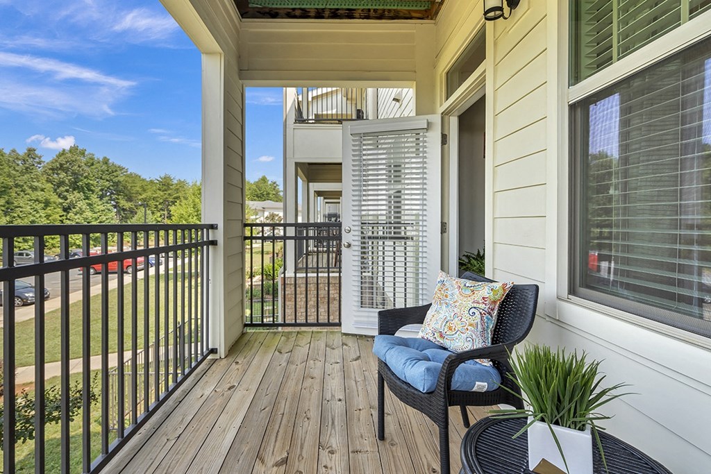 the back porch of a home with a chair and a table