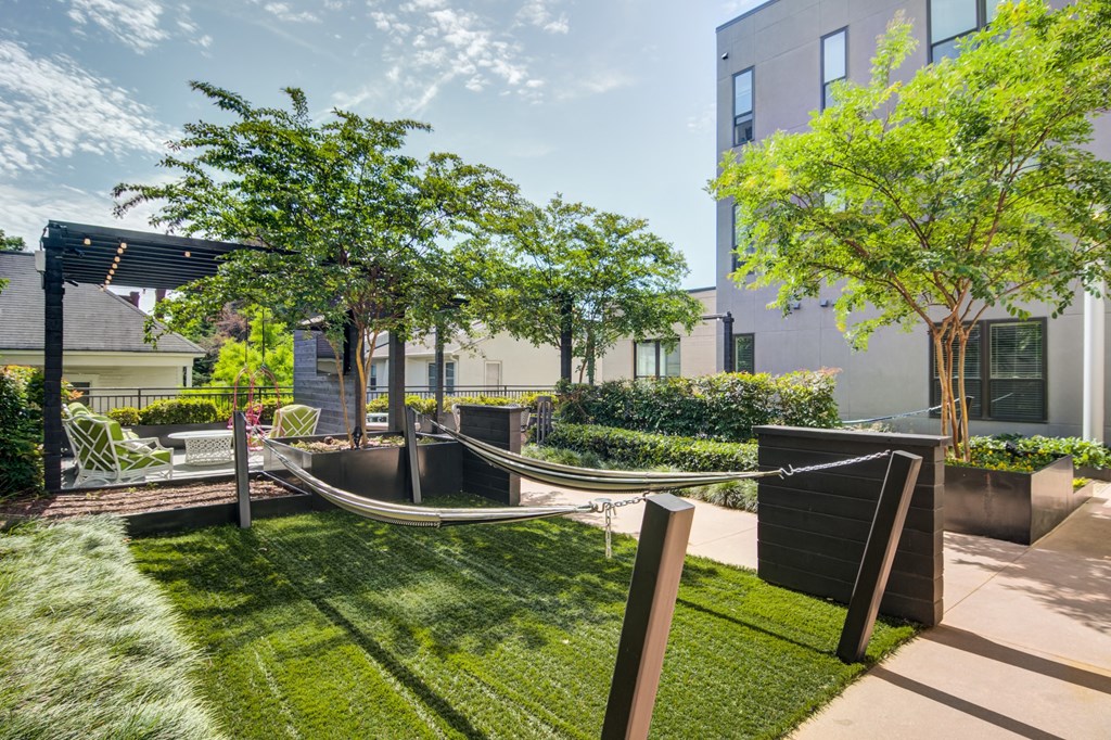 a yard with a hammock and trees and a building