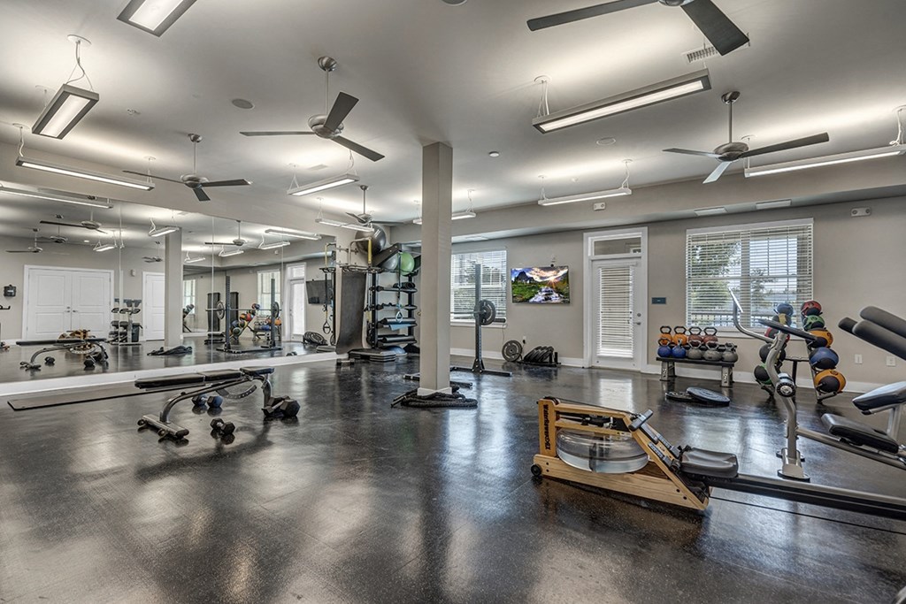 a workout room with weights and other exercise equipment at the enclave at university crossings apartments