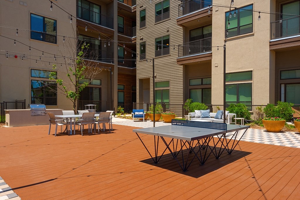 a patio with tables and chairs in front of an apartment building